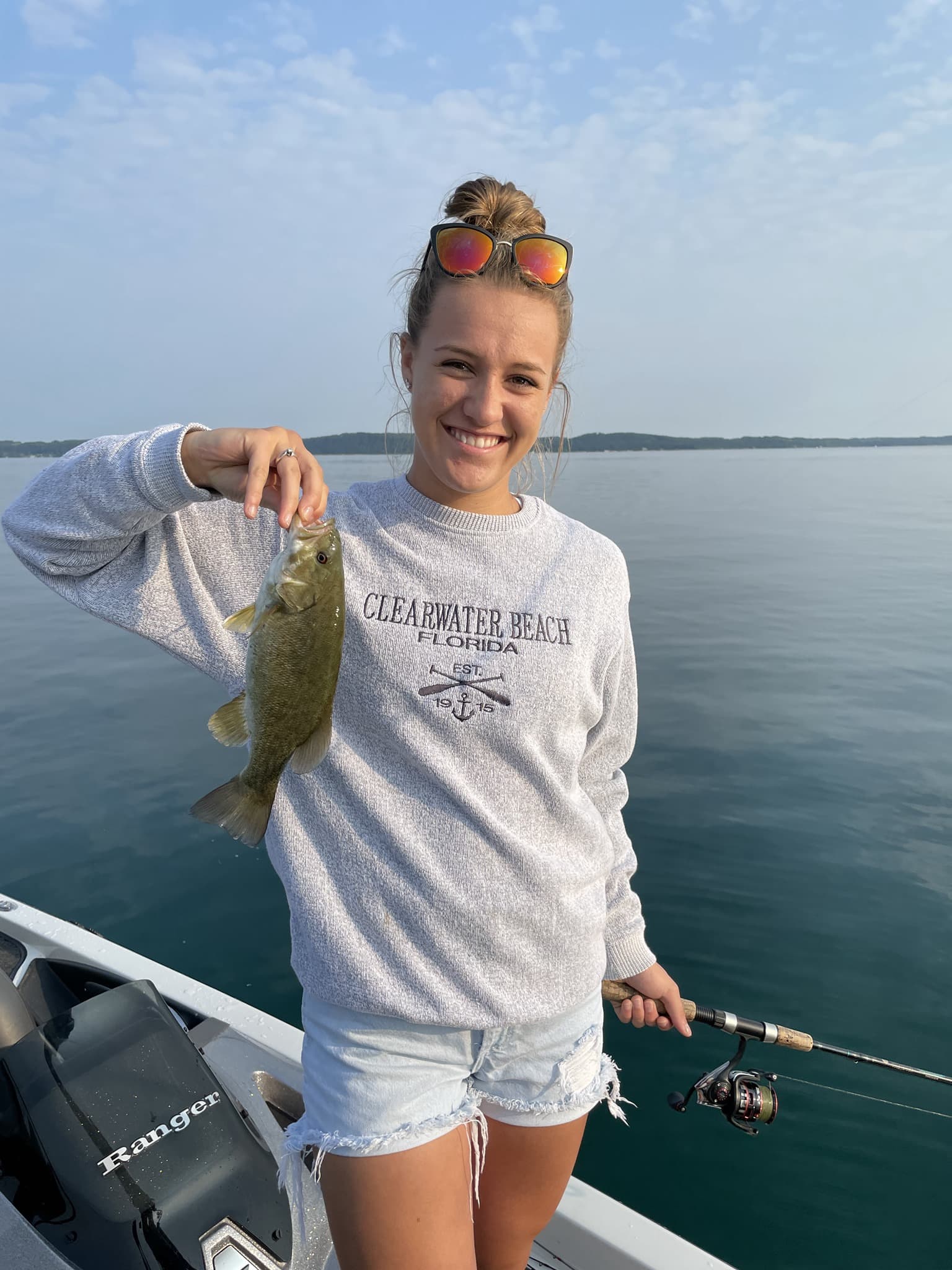Woman with bass catch on calm water